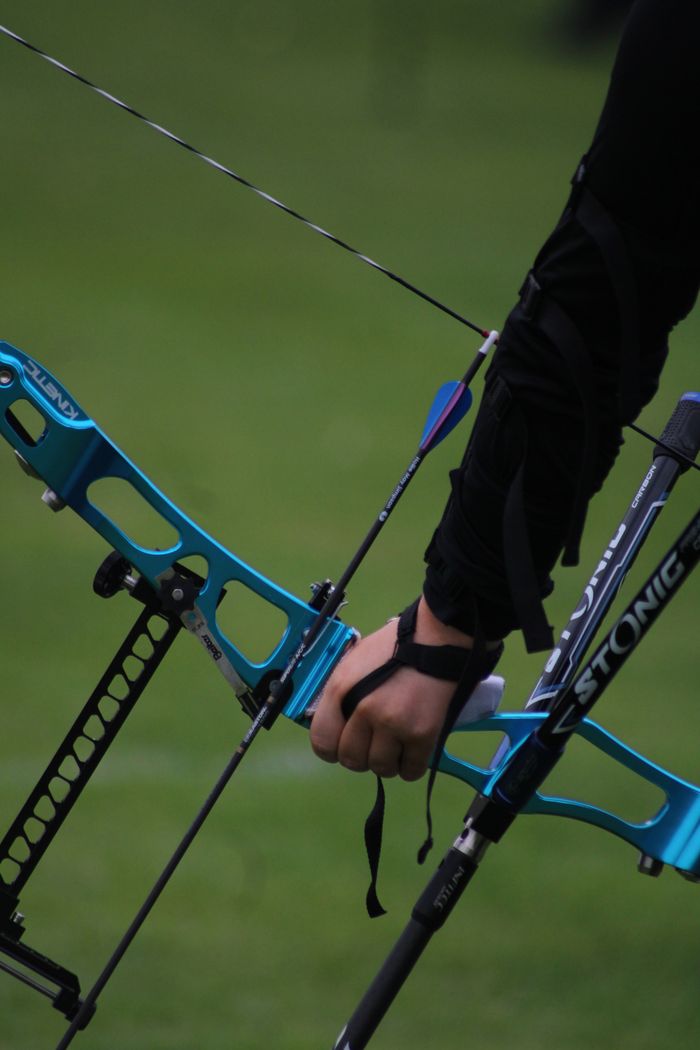Detailed shot of an archer's hand holding a compound bow, preparing for action.